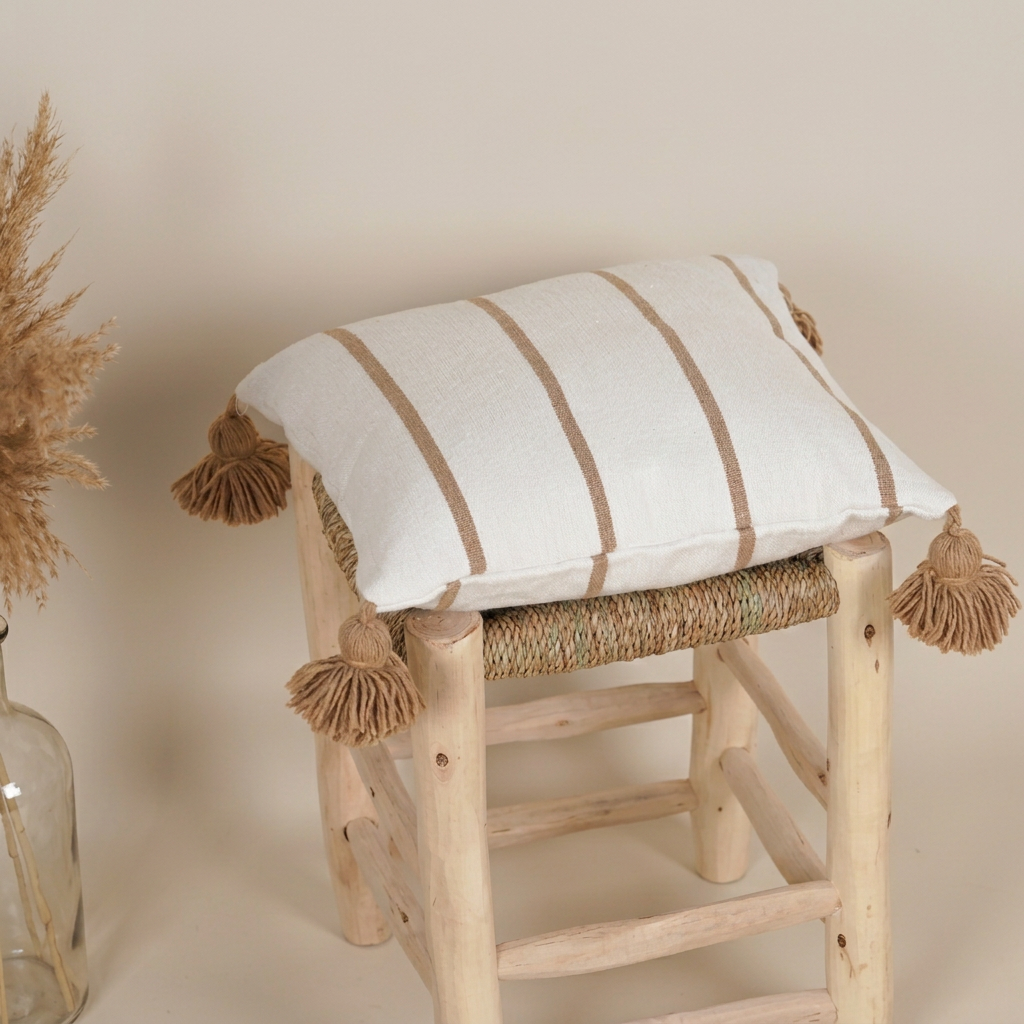 Pomponkussen op kruk met zachte beige achtergrond